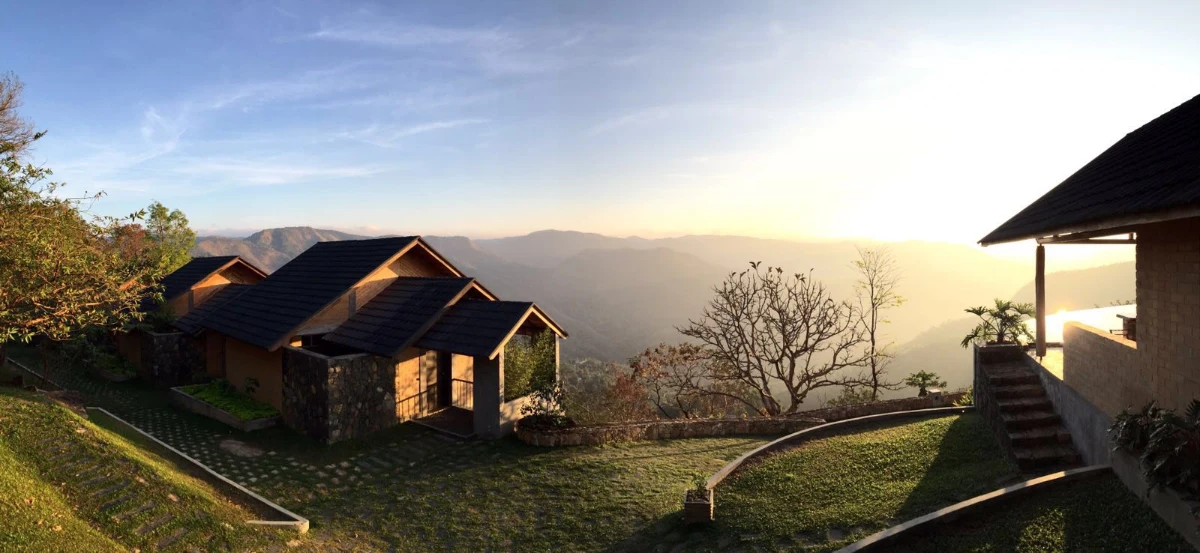Cottage with private balcony overlooking lush Kerala valley landscape.