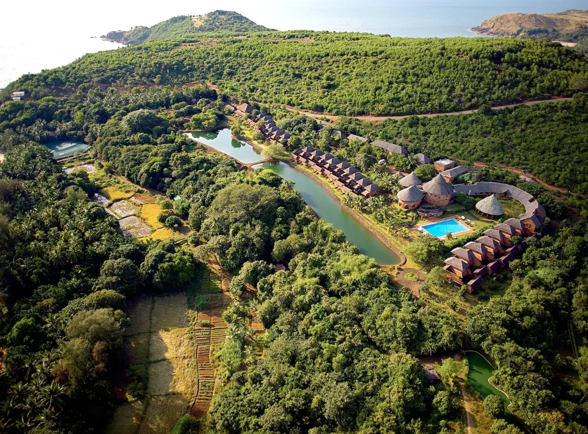 Aerial view of traditional Konkan villas overlooking Om Beach at sunrise.